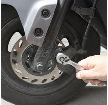 O persoană folosește o cheie cu clichet pe o motocicletă.