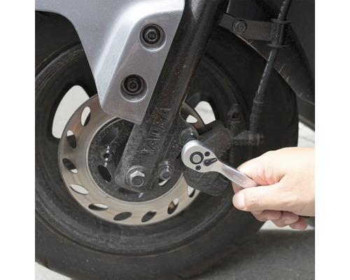 O persoană folosește o cheie cu clichet pe o motocicletă.