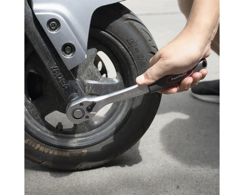 Cheie cu clichet strângând o anvelopă de motocicletă.