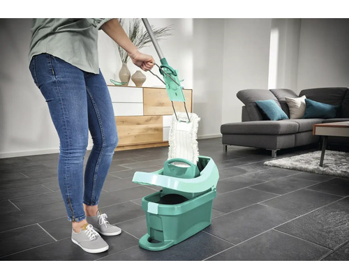 Femeie folosind un mop cu găleată în sufragerie pentru curățarea podelei