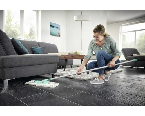 Femeie șterge podeaua în camera de zi cu mopul