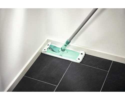 Mop pe podea cu gresie închisă la culoare, lângă un perete alb