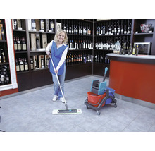 Femeie de serviciu șterge o podea de gresie într-un magazin de vinuri cu un mop și o găleată.