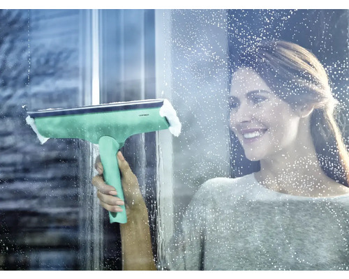 Femeie curăță geamurile cu o racletă pentru geamuri