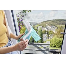 Femeie care folosește un ștergător de geamuri cu husă din microfibră pentru a curăța o fereastră