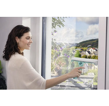 Femeie curățând geamurile cu un racletă pentru o curățare fără urme