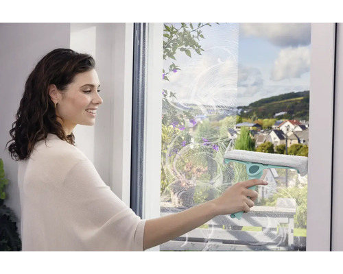 Femeie curățând geamurile cu un racletă pentru o curățare fără urme