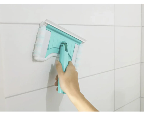 Mână folosind un ștergător de geamuri cu husă din microfibră pe un perete faianțat