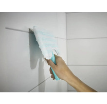 O mână șterge plăcile de faianță cu un mop plat