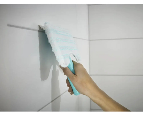 O mână șterge plăcile de faianță cu un mop plat