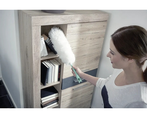 Femeie curăță raftul cu un pămătuf