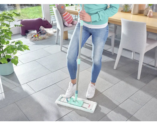 Femeie șterge podeaua cu mopul într-un living