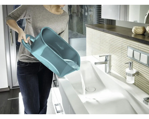 Femeie care golește o găleată multifuncțională într-o chiuvetă din baie