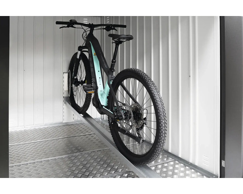 Bicicletă electrică de munte pe o rampă într-un spațiu de depozitare.