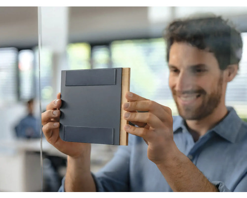 Bărbat atașează un indicator magnetic de ușă pe o ușă de sticlă în birou