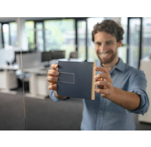 Un bărbat fixează o plăcuță de ușă pe o ușă de sticlă într-un birou.