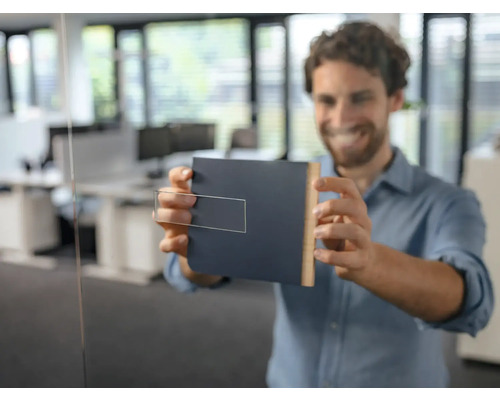 Un bărbat fixează o plăcuță de ușă pe o ușă de sticlă într-un birou.