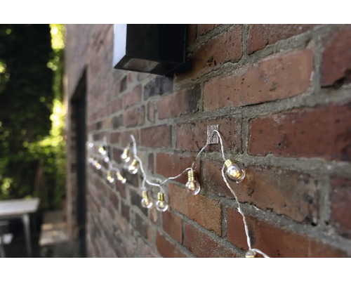 Ghirlandă luminoasă cu becuri fixată pe un zid de cărămidă