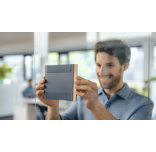 Un bărbat atașează o plăcuță de ușă pe o ușă de sticlă