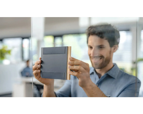 Un bărbat atașează o plăcuță de ușă pe o ușă de sticlă