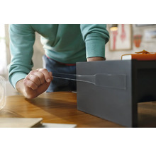 O persoană fixează o bandă adezivă pe un raft gri.