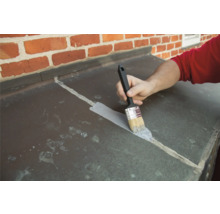 O persoană sigilează cu o pensulă rosturile unei placări din tablă.