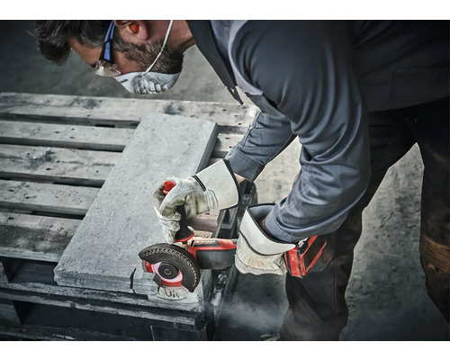 O persoană taie pietre cu un polizor unghiular, purtând echipament de protecție.