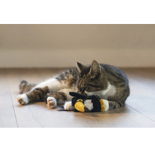 Pisică tigrată stând întinsă cu o jucărie pe podea.