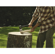 Bărbat care taie lemne cu un topor pe un butuc.