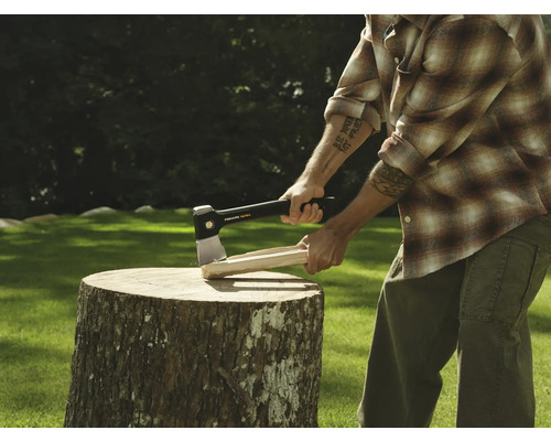 Bărbat care taie lemne cu un topor pe un butuc.