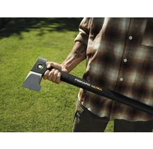 Persoană care ține un topor de despicat Fiskars Ultra pe un fundal verde