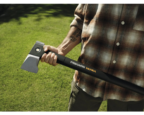 Persoană care ține un topor de despicat Fiskars Ultra pe un fundal verde