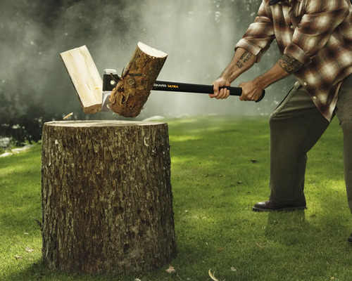 Bărbat despărțind un buștean cu un topor pe un ciot