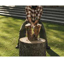 Bărbat despărțind lemne pe un butuc cu un topor.