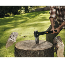 Bărbat care taie lemne cu un topor Fiskars pe un ciot de copac în aer liber