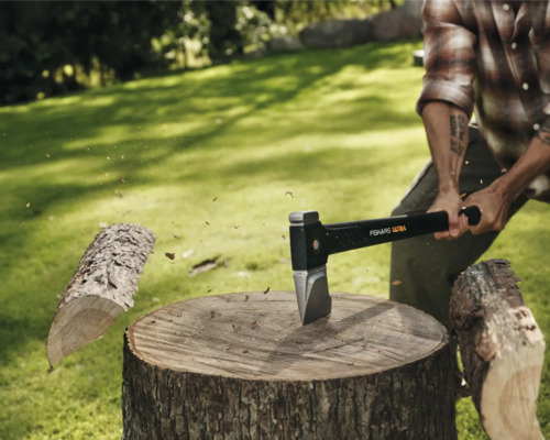 Bărbat care taie lemne cu un topor Fiskars pe un ciot de copac în aer liber