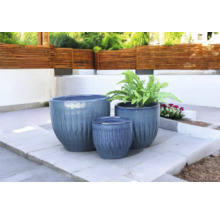 Trei jardiniere de diferite dimensiuni pe o terasă