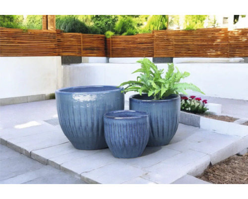 Trei jardiniere de diferite dimensiuni pe o terasă