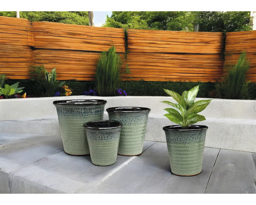 Patru vase de ceramică pentru plante de diferite dimensiuni în grădină.