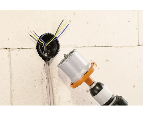 Mașină de găurit cu ferăstrău carotier lângă o priză de perete cu cabluri