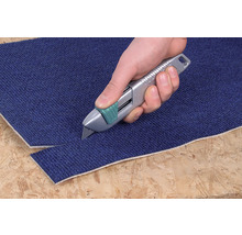 O mână taie un covor cu un cuțit de covoare.