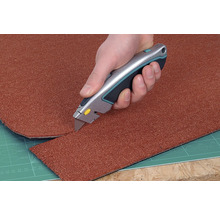 Un covor este tăiat la dimensiune cu un cuțit pentru covoare.