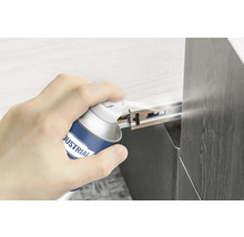 O mână pulverizează spray lubrifiant pe un glisor de sertar.