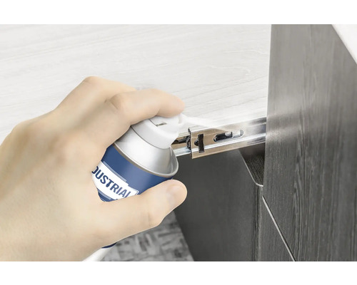 O mână pulverizează spray lubrifiant pe un glisor de sertar.