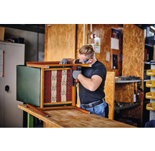 Artizan fixează tapițeria de un scaun cu un capsator