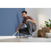 Bărbat aplicând bandă de mascare de-a lungul peretelui pentru renovare