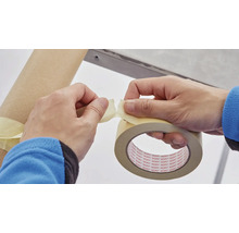 Persoană rupe bandă de mascare pentru a fixa un obiect.