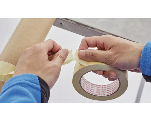 Persoană rupe bandă de mascare pentru a fixa un obiect.