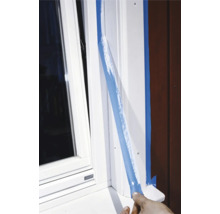 Aplicarea benzii de mascare pe un toc de fereastră alb pentru lucrări de vopsire.