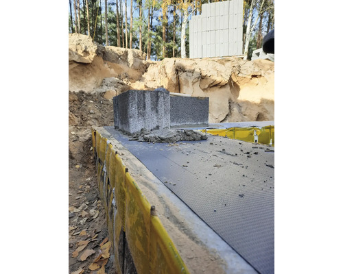 Imagine cu blocuri de beton așezate pe un strat izolator într-o groapă de construcție